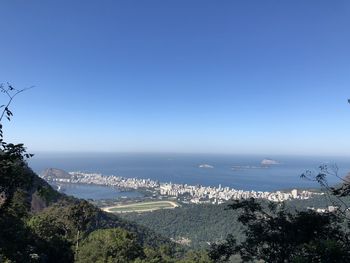 Scenic view of sea and mountains against clear blue sky