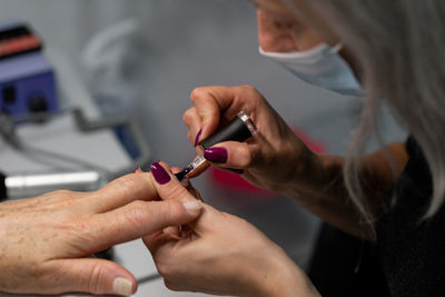 Senior woman in cosmetic salon doing manicure with specialist