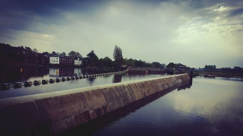 View of river in city against cloudy sky