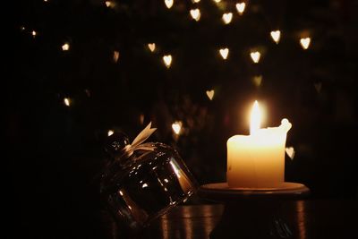 Close-up of burning candle on table at night