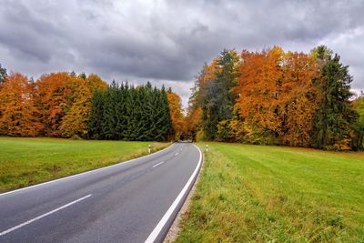 Road amidst trees against sky during autumn