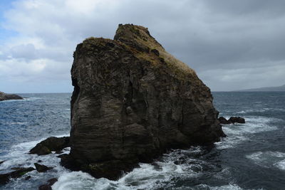 Rock formations amidst sea against cloudy sky