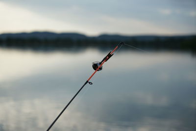 Fishing rod over lake against sky