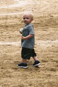 Full length portrait of cute boy standing on field