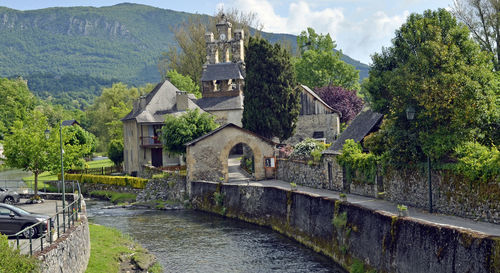 Bridge over river amidst buildings and trees against sky