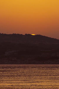 Scenic view of silhouette landscape against orange sky