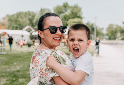 Portrait of happy mother holding son, both looking at camera