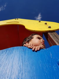 Girl looking at swimming pool against blue sky