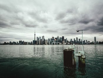 Sea by modern buildings against sky in city