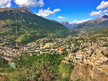 Aerial view of townscape by mountains against sky