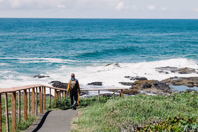 Man with a backpack going down to the beach, hiking on the coast of oregon