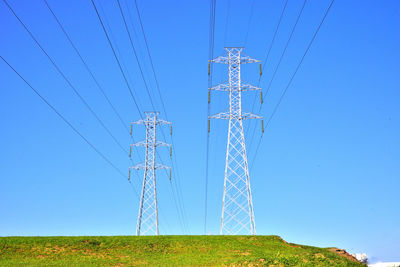 Low angle view of electricity pylon against clear blue sky