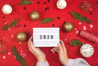 Cropped hands holding 2020 message over christmas decorations