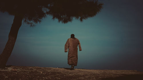 Rear view of woman walking on field