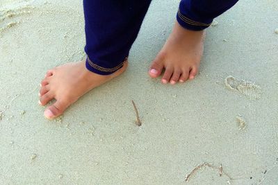 Low section of man standing on sand