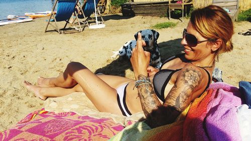 Full length of tattooed woman resting at beach during summer