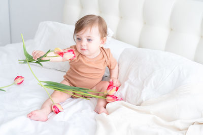 Portrait of cute girl playing with teddy bear on bed at home