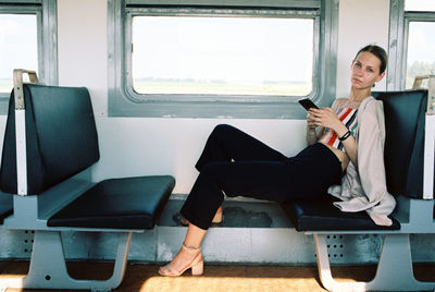 Portrait of woman using phone sitting in train