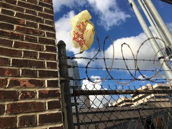 Low angle view of plastic bag stuck on razor wire fence