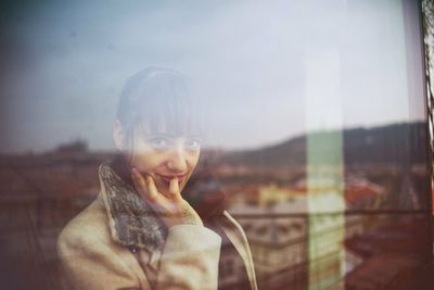 Portrait of smiling young man looking through window