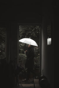 Man holding umbrella seen through doorway