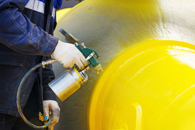 Midsection of man working on yellow pipe