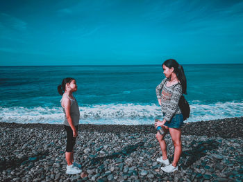 Sisters standing on beach against sky