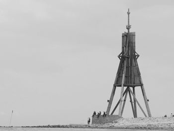 Lighthouse on beach against clear sky