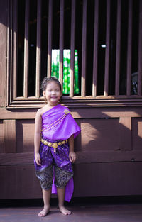 Portrait of smiling girl standing against purple outdoors