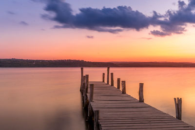 Pier over lake against sky during sunset