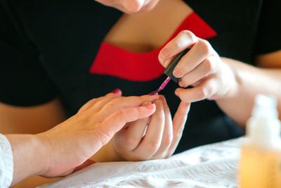 Midsection of woman applying nail polish to girl at home