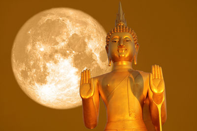 Digital composite image of statue against illuminated temple