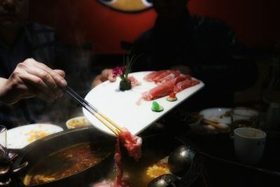 Cropped image of hand having shabu-shabu at restaurant