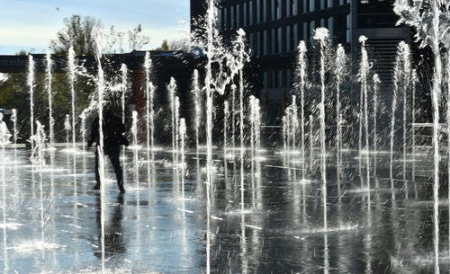 Water splashing on fountain against trees and building