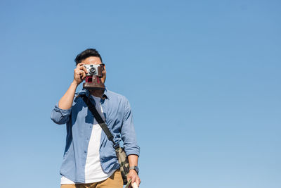 Man photographing against clear blue sky