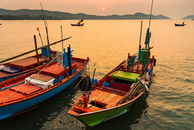 Fishing boats moored in sea against sky