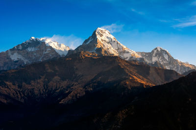 Scenic view of snowcapped mountains against blue sky