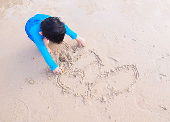 High angle view of boy playing on sand at beach