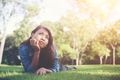 Thoughtful young woman lying on grass at park