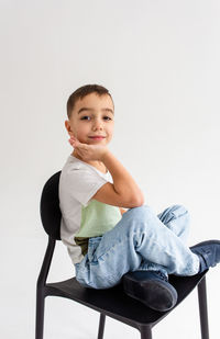 Portrait of boy sitting against white background