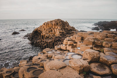 Rocks on shore by sea against sky