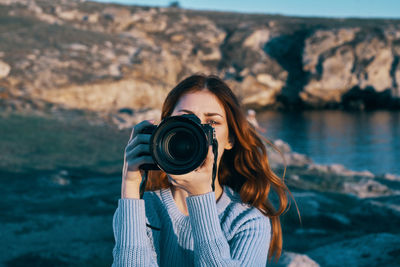 Portrait of young woman photographing camera