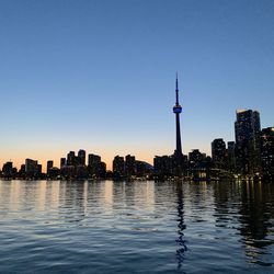 Sea by modern buildings against clear sky