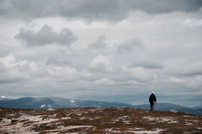 Rear view of man on mountain against cloudy sky