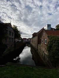 Canal amidst houses and buildings against sky