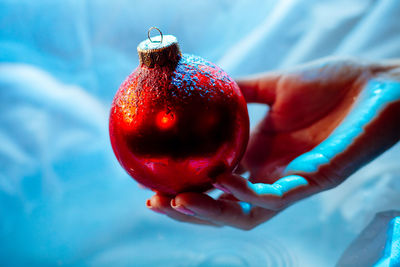 Close-up of hand holding bauble over water