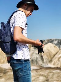 Young man holding camera with rock formation in background