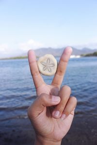 Close-up of hand holding sea against sky