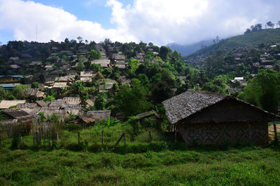 Houses on field by buildings against sky