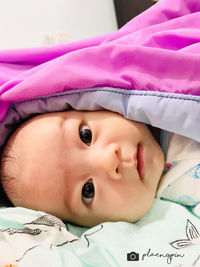 Close-up portrait of cute baby lying on bed